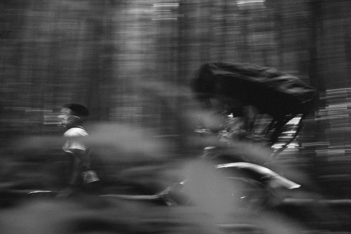 Cyclist speeding through a forest in motion blur, Ilford Delta 3200 preset applied