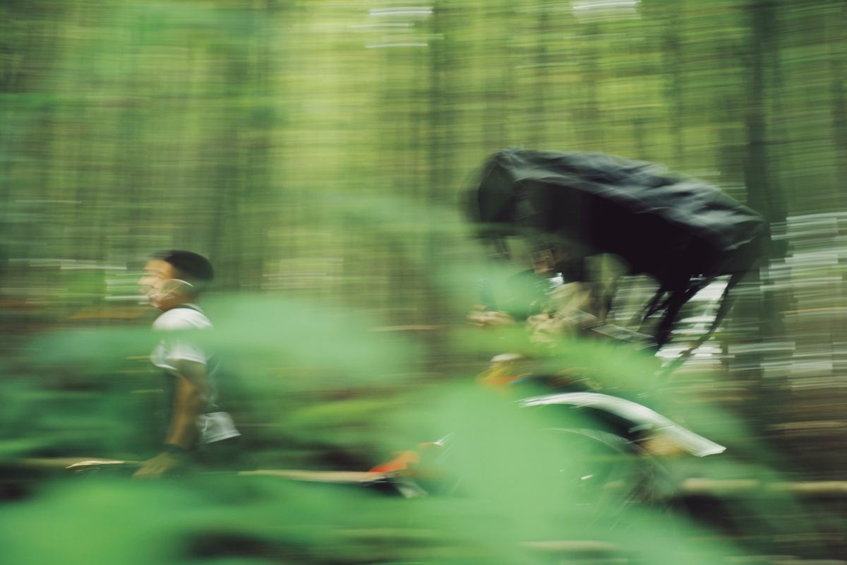 Cyclist speeding through a forest in motion blur, Fuji Superia 1600 preset applied