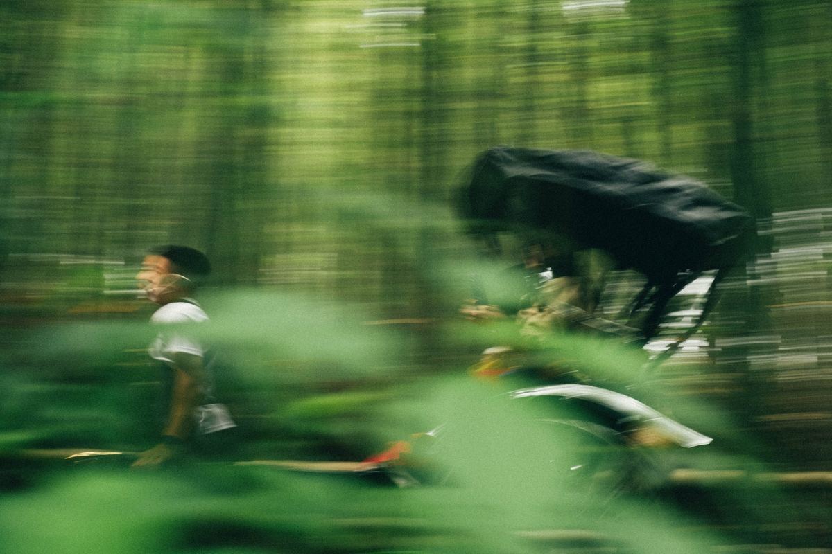 Cyclist speeding through a forest in motion blur, Fuji Superia 800 preset applied