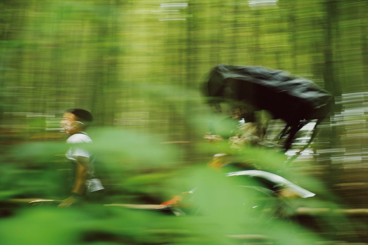 Cyclist speeding through a forest in motion blur, Kodak Portra 160 NC preset applied