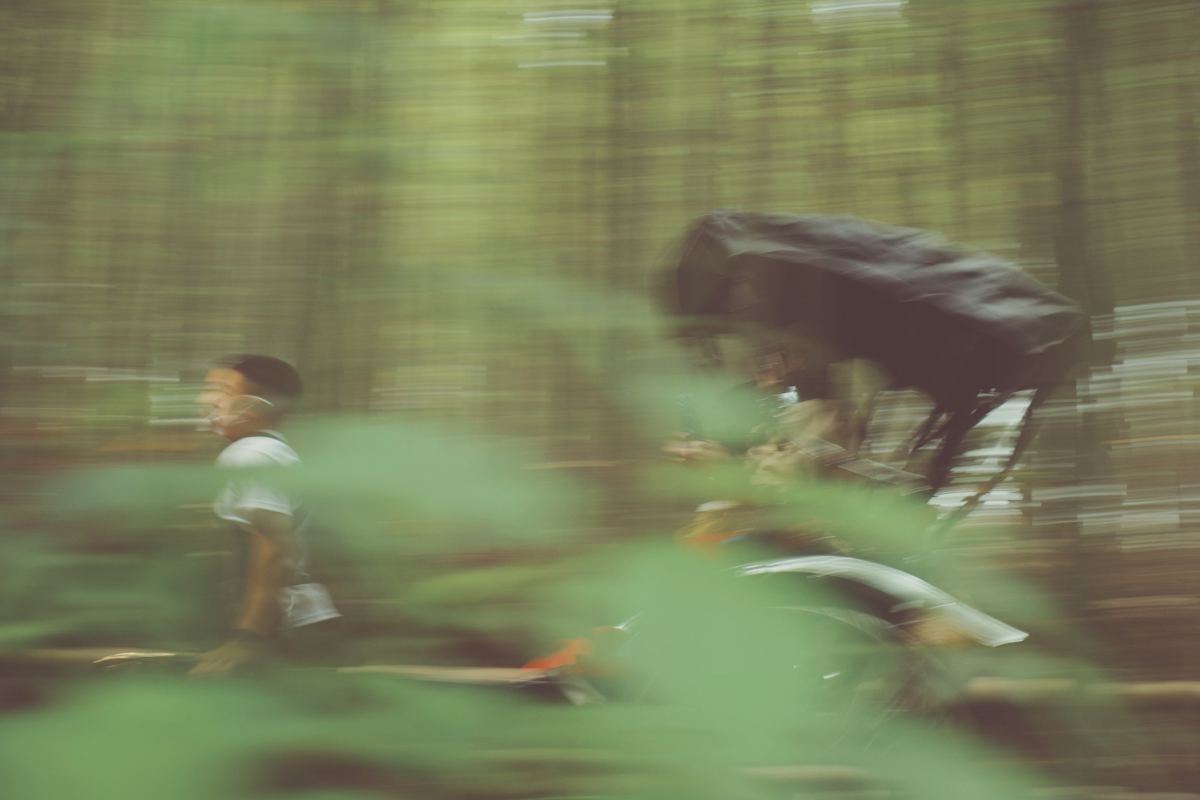 Cyclist speeding through a forest in motion blur, Kodak Portra 400 UC preset applied