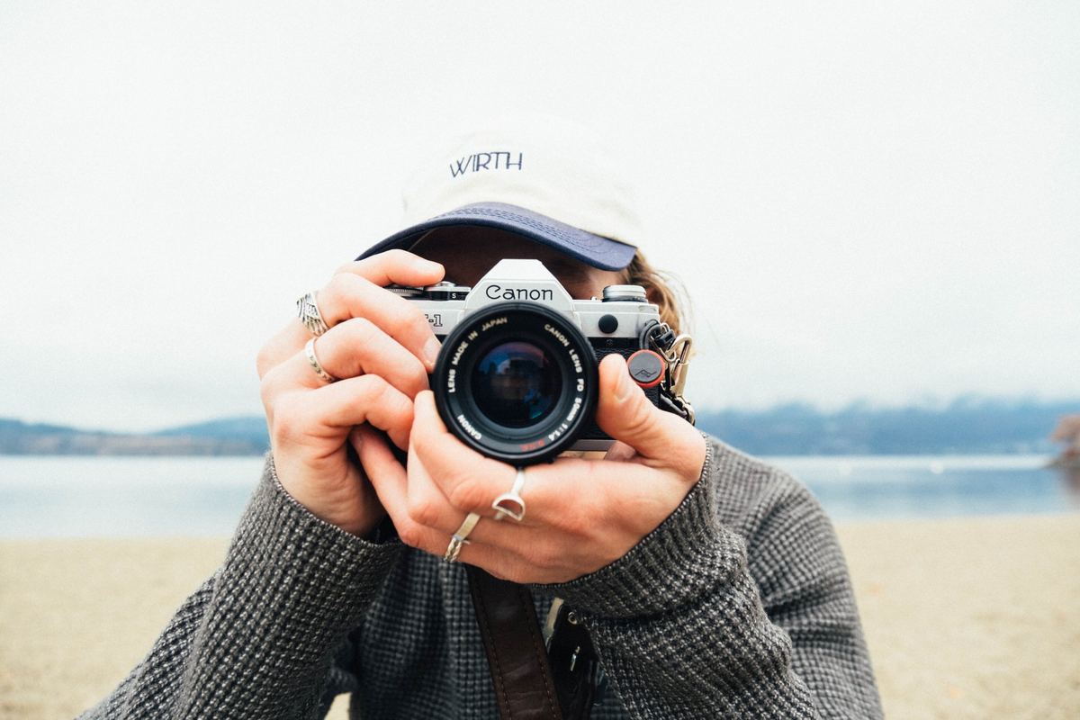 Photographer holding a film camera up to their face on a lakeshore, Kodak UltraMax 400 preset applied