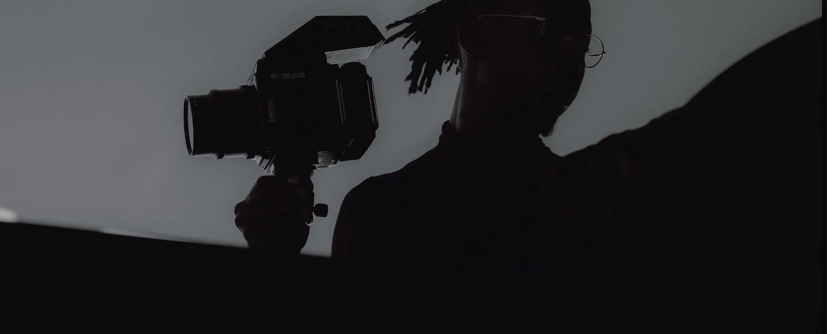 Black and white silhouette of a photographer with a medium format camera on a tripod.
