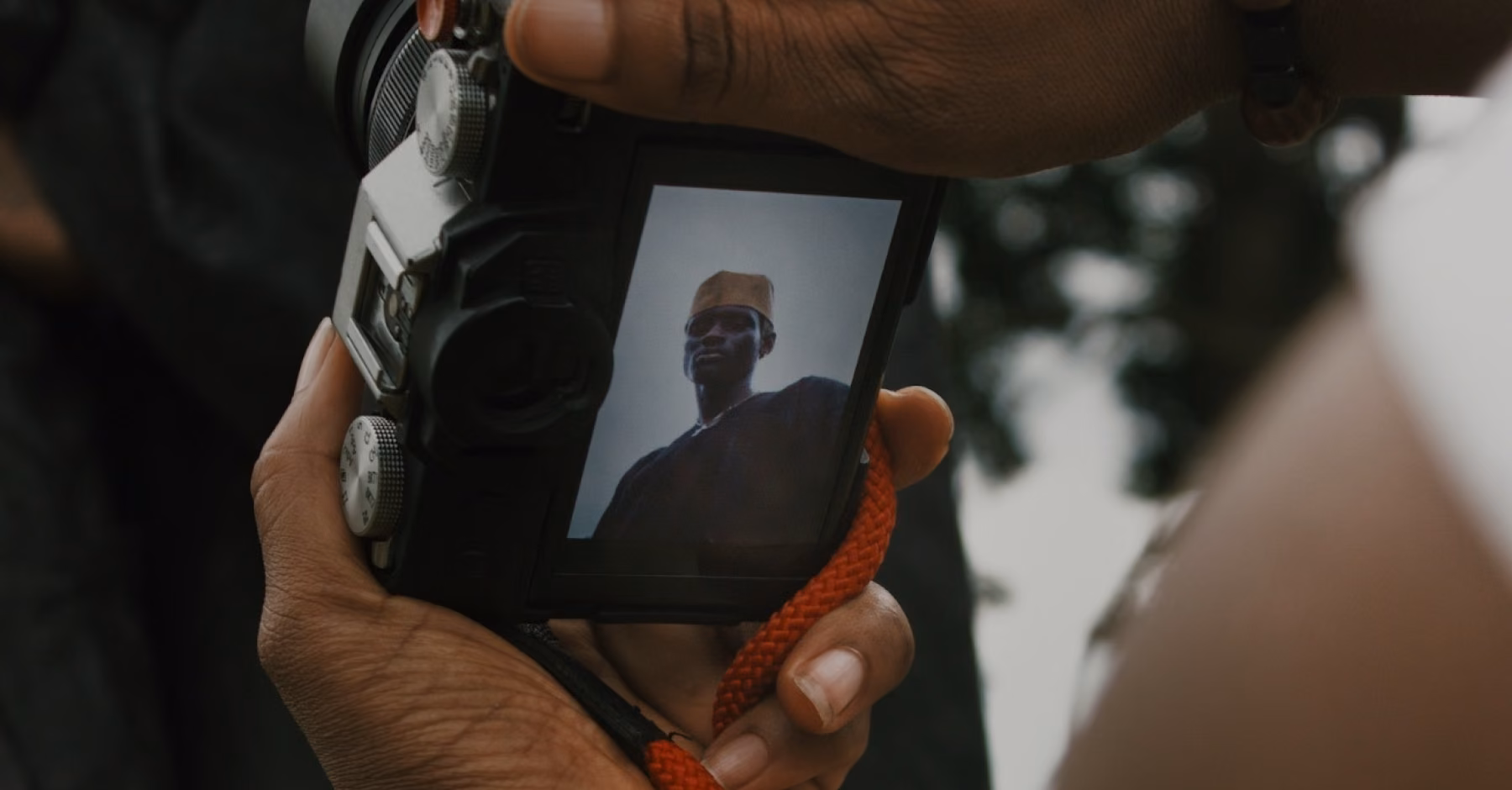 Hands holding a camera showing a portrait on the screen.