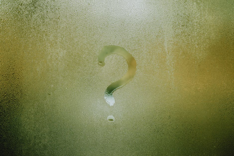 A question mark drawn on foggy glass, evoking curiosity and mystery.