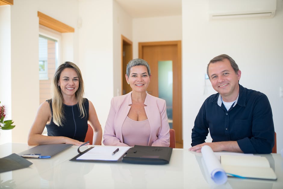 Three professionals smiling at a business meeting in a modern office.