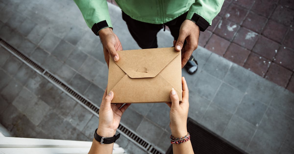 Close-up of hands exchanging a brown envelope outdoors on a pavement scene.