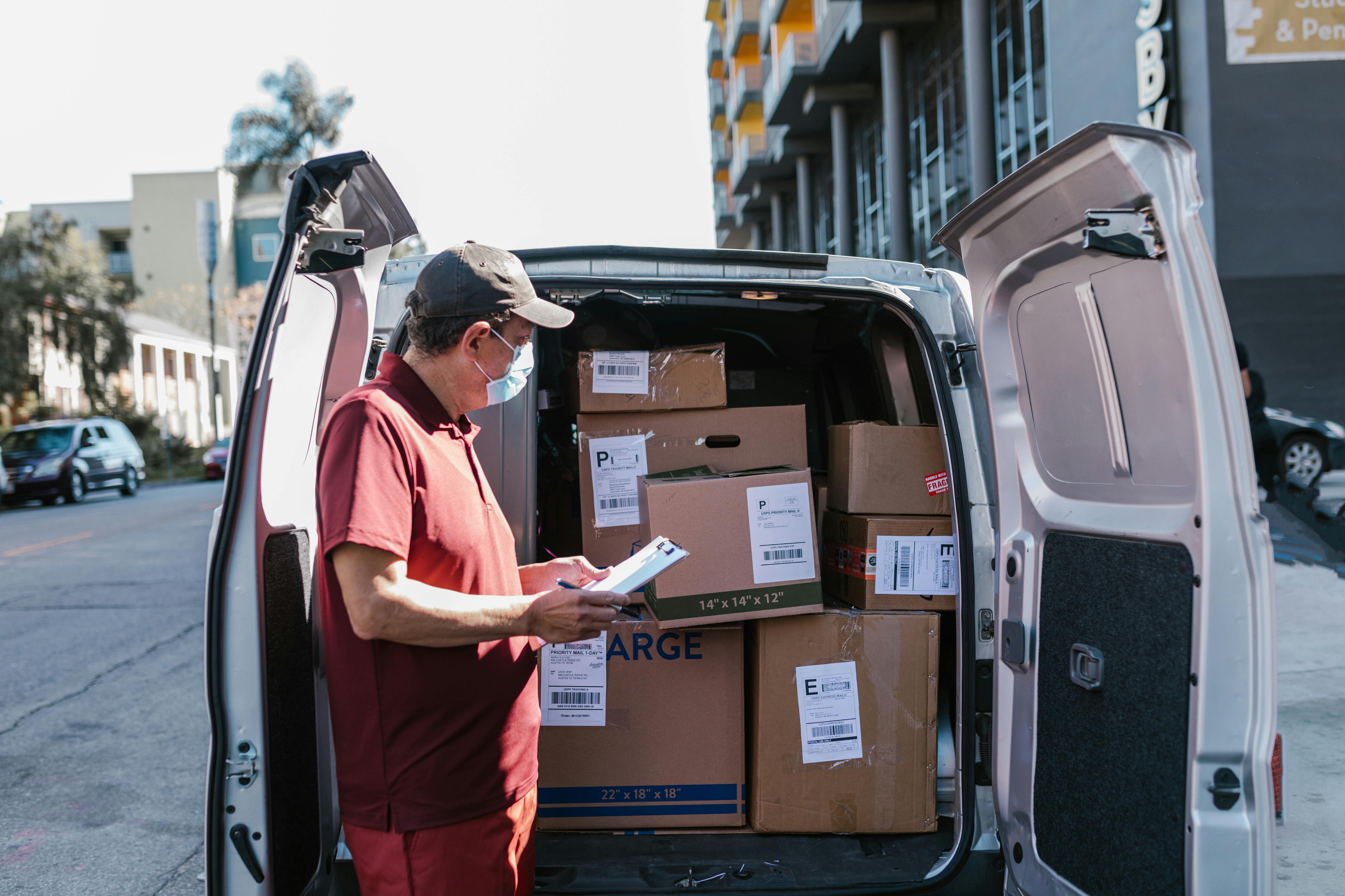 Delivery worker checks packages in a van on a city street, ensuring orders are ready for shipping.