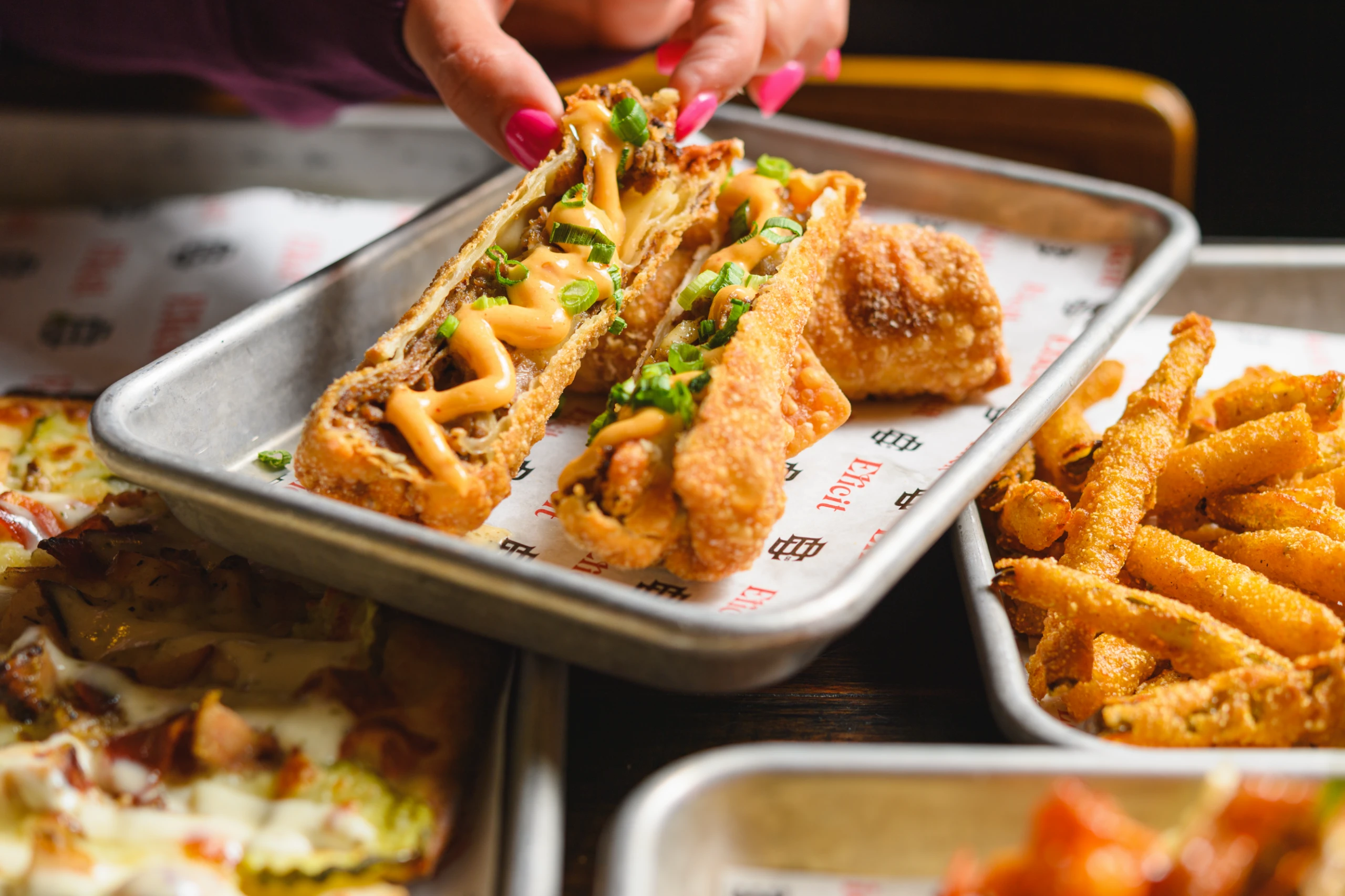 An image of a crispy cheese roll served with fries at Elicit Brewing.