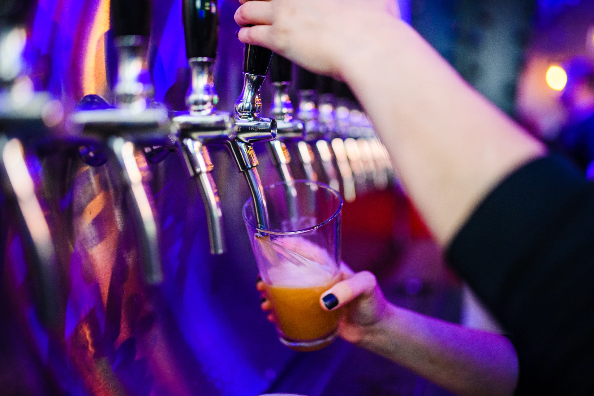 an image of a bartender pouring beer from a tap at Elicit Brewing’s tapstation.