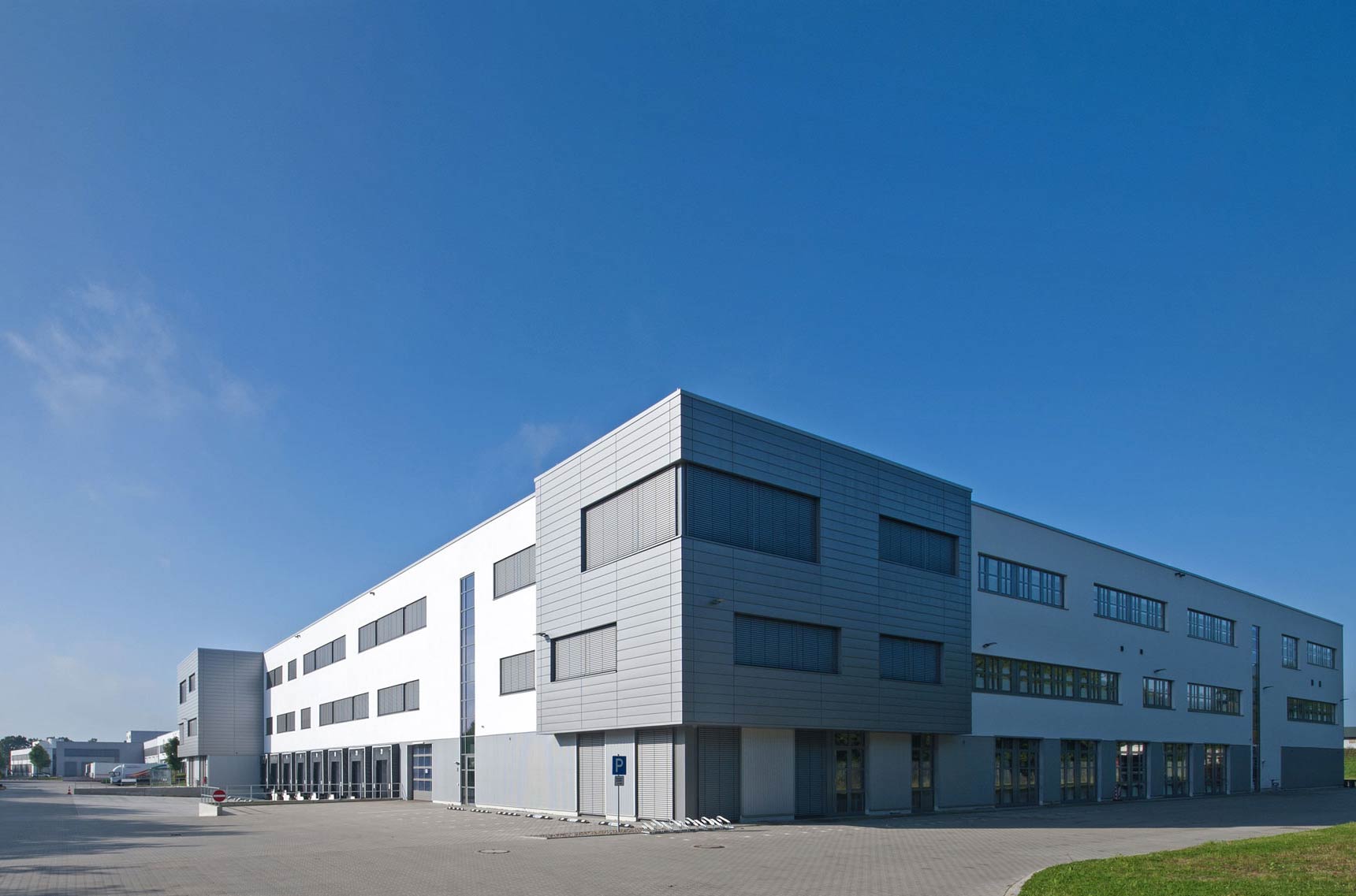 Ein gelber Lkw parkt vor einem großen Logistikzentrum.