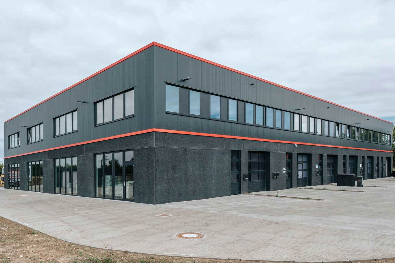Verwaltungsgebäude mit rotem Streifen, neu errichtet, bietet attraktive Büroflächen zur Vermietung an.