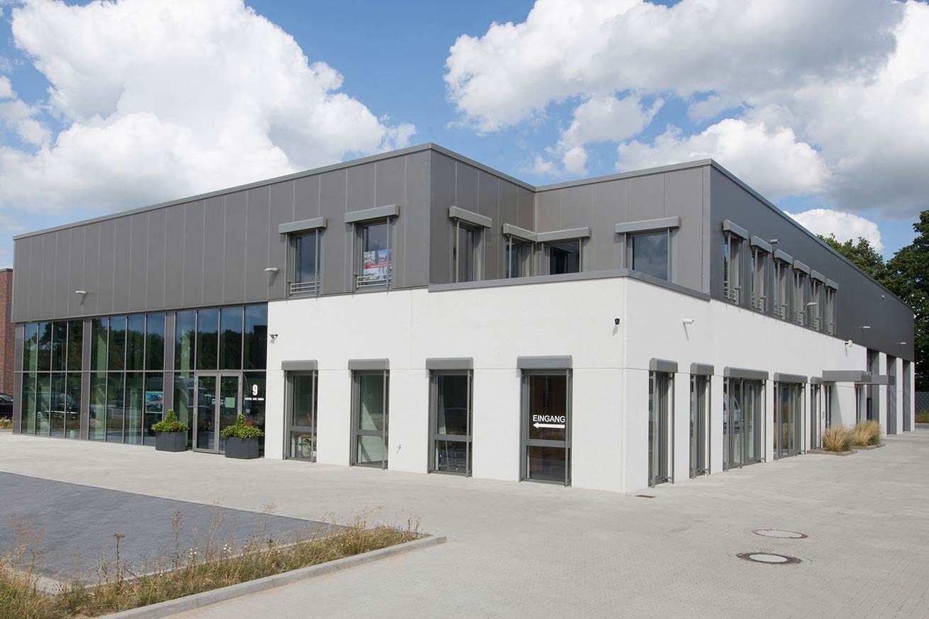 Großes weißes Betriebsgebäude eines Wohnmobilhändlers mit angrenzendem Parkplatz.
