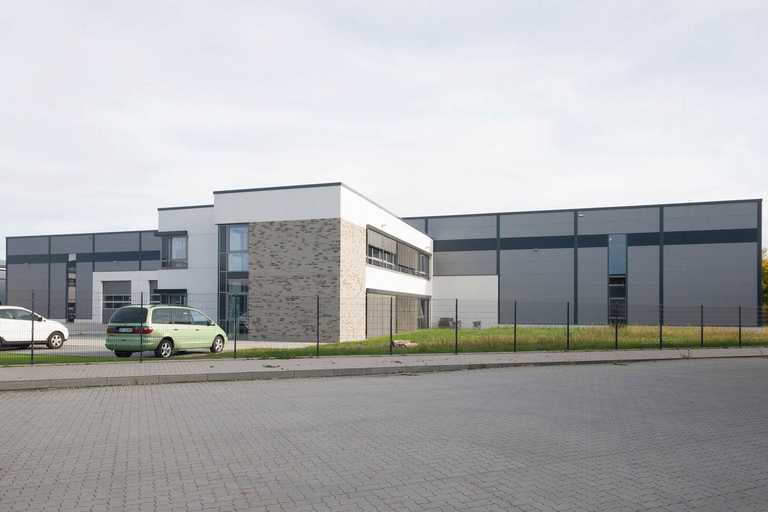 Weißes Gebäude für die Herstellung von Formteilen in der Kunststofftechnik, Auto parkt davor.