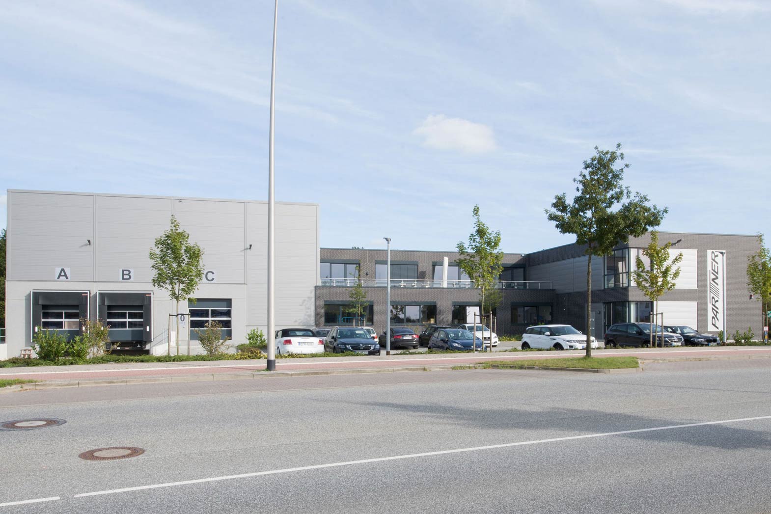 Industriegebäude mit Werkstatt für Kassensysteme, umgeben von parkenden Fahrzeugen.