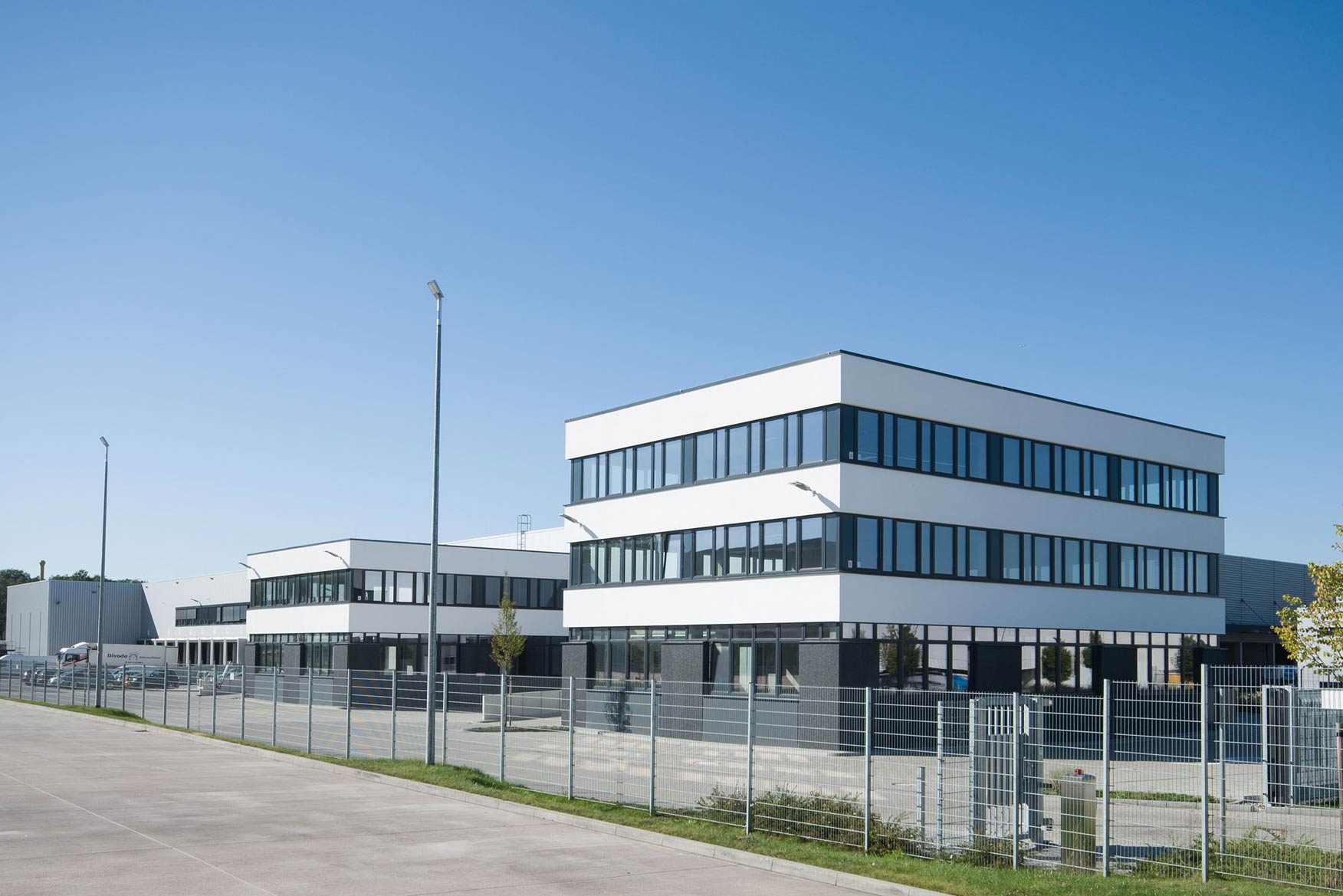 Ein gelber Lkw parkt vor einem großen Logistikzentrum.