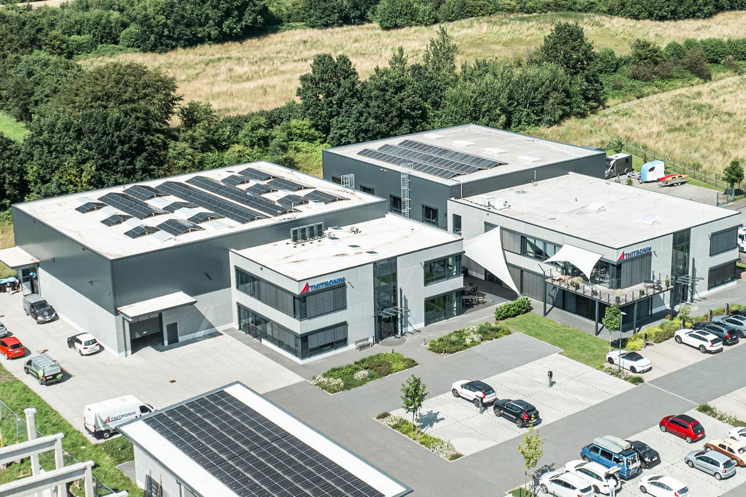 Großes Betriebsgebäude mit Lager und Werkstatt eines Maschinenbau-Unternehmens mit einer Straße im Vordergrund.