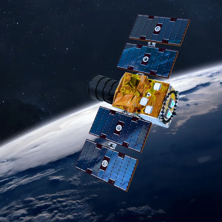 Satellite with multiple solar panels orbiting above Earth with a view of clouds and ocean.