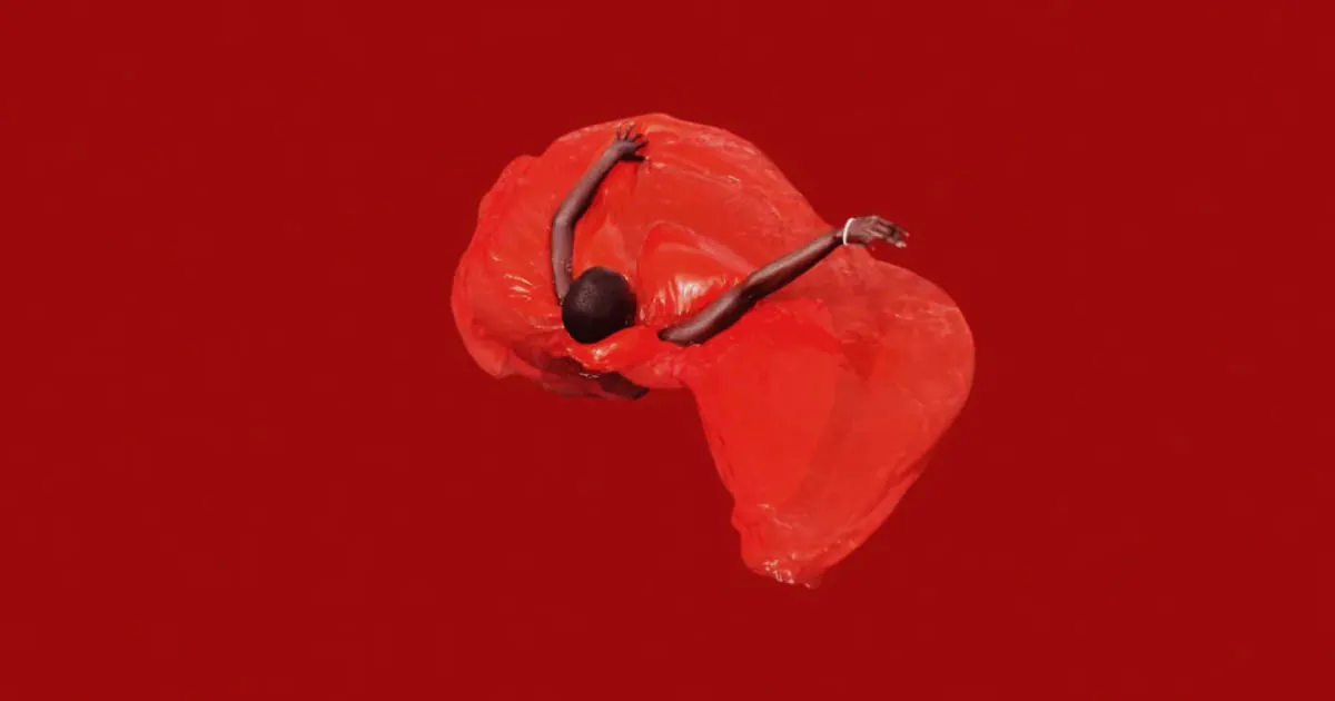 Professional fashion photoshoot of someone twirling in a red dress with a red background shot from above by photographer John Baloy