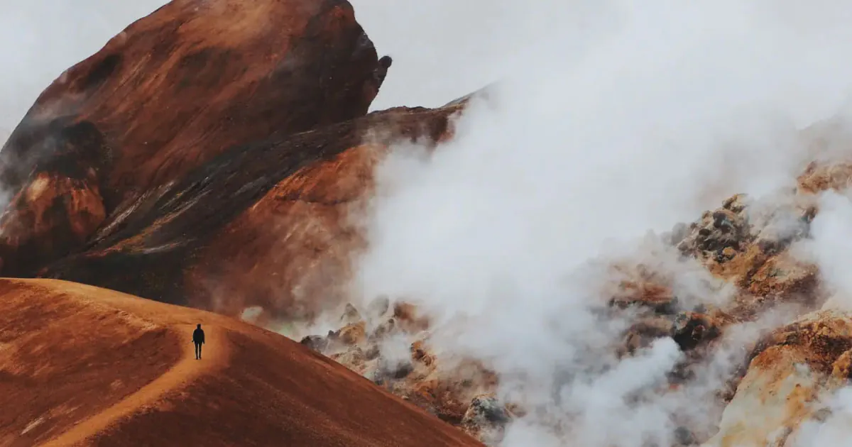 Hiker on red hills with low clouds taken by photographer sannalinn on VSCO