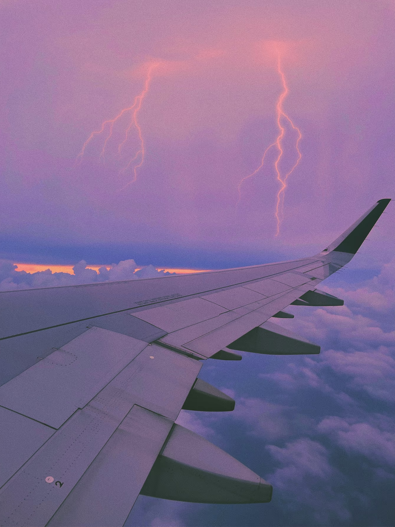 Lightning and airplane wing in a pinkish purple sky by Tess Burris