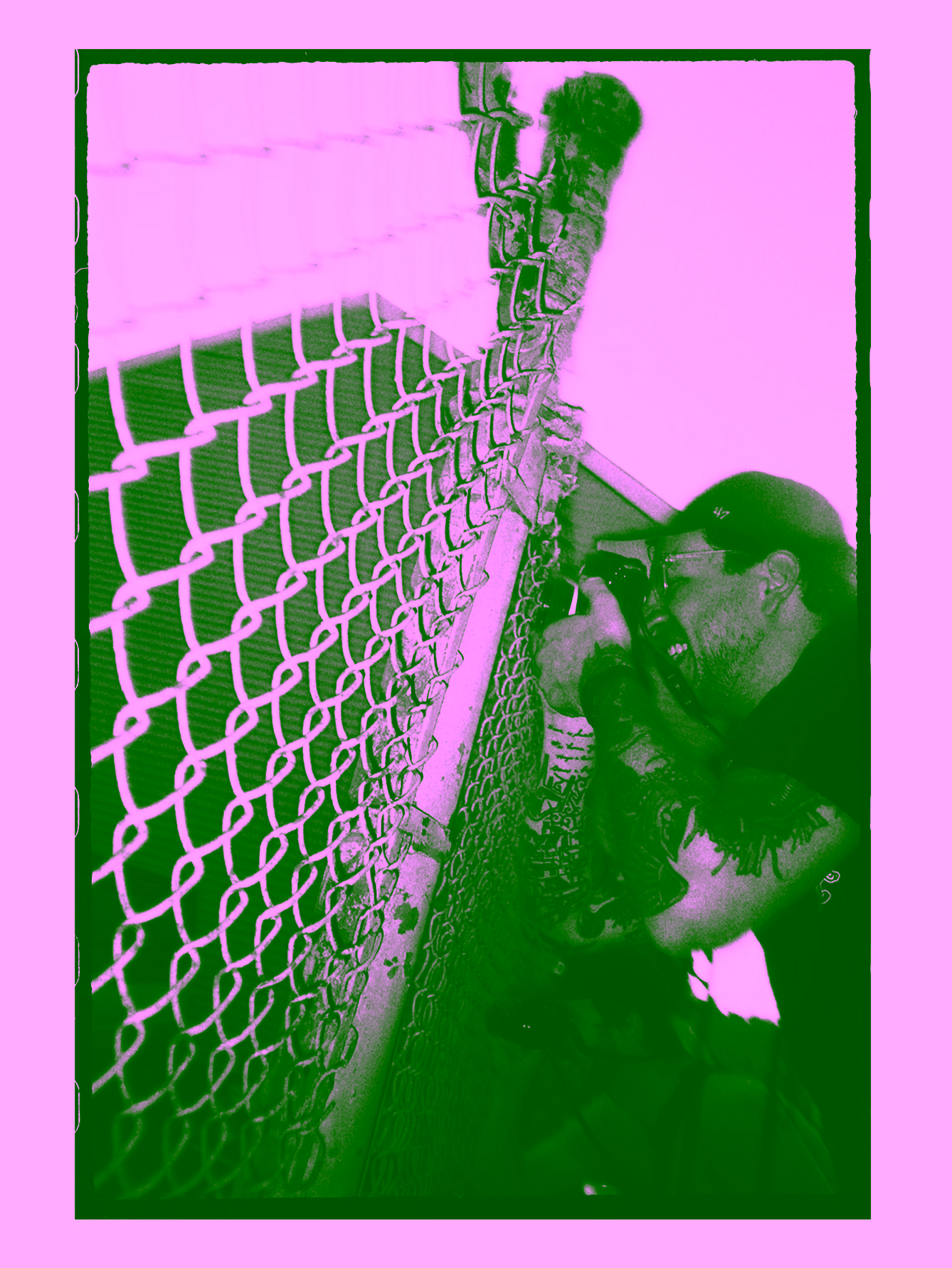 Black and white photo of photographer taking a picture between a chain fence