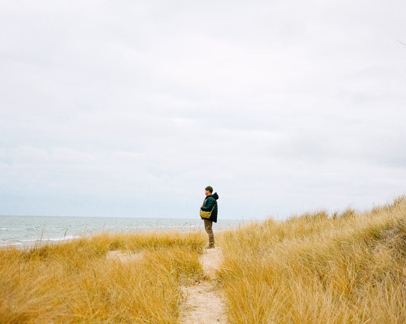 Man standing in tall grass at the cold ocean coast