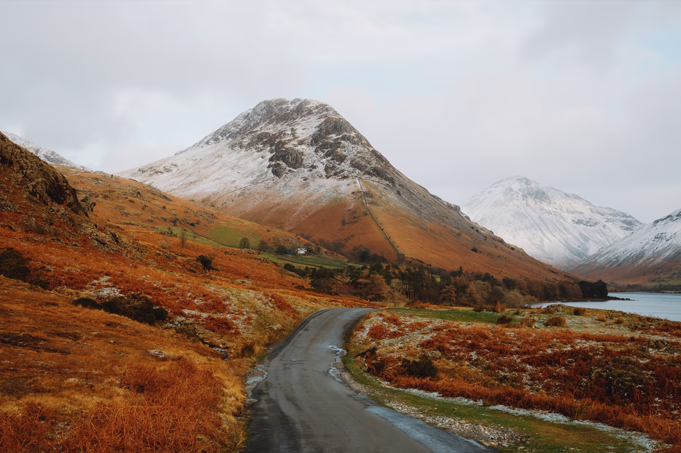 Landscape photo with fall colors and light snow on mountain tops and a winding road
