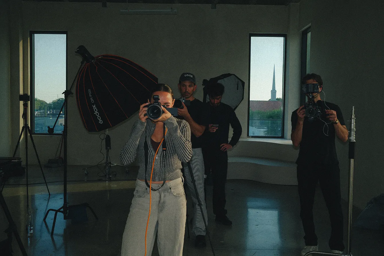 Pro photographer holding a camera with crew behind on photoshoot set
