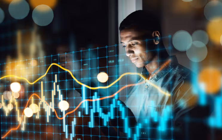 Uomo che analizza grafici finanziari digitali con linee luminose e grafici a barre in una stanza buia.