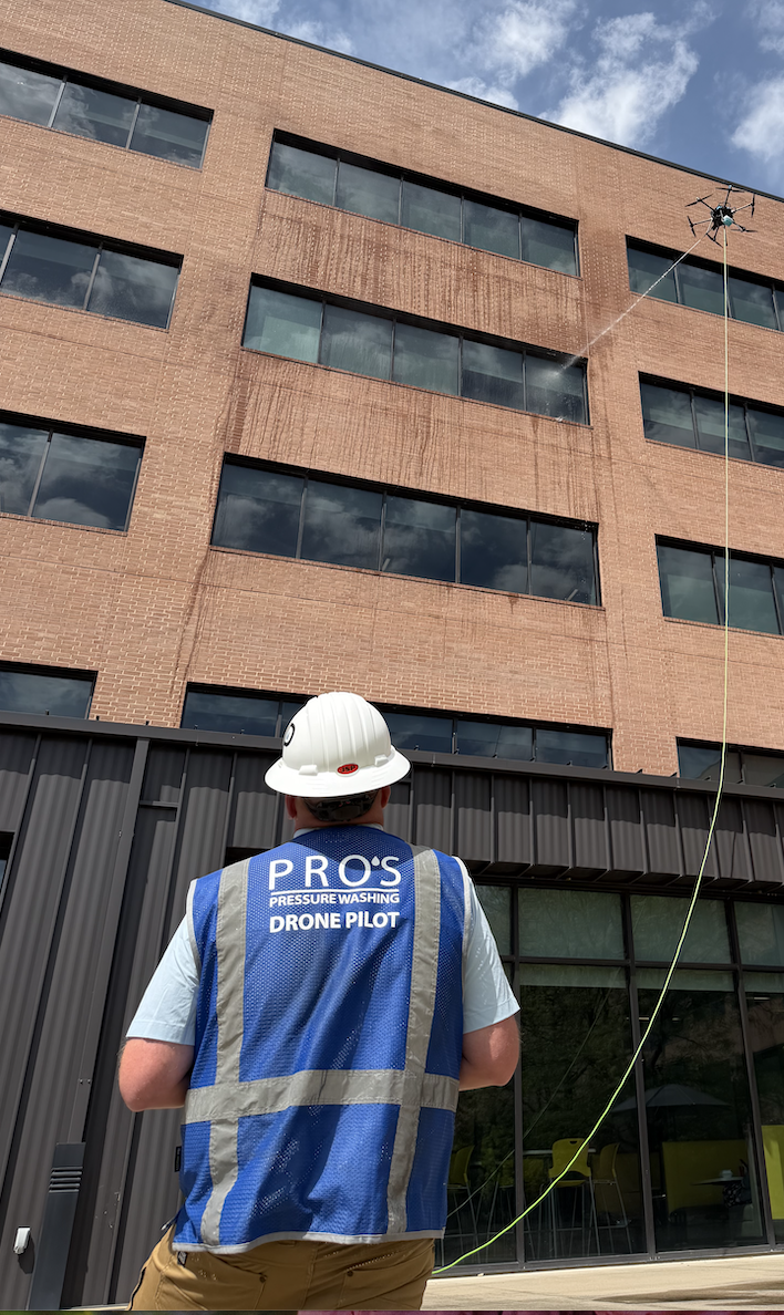 Pro's Pressure Washing pilot in a blue Drone Pilot vest flying the drone on a jobsite