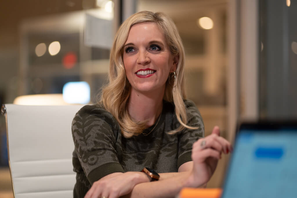 A woman sitting in a meeting room smiliing.