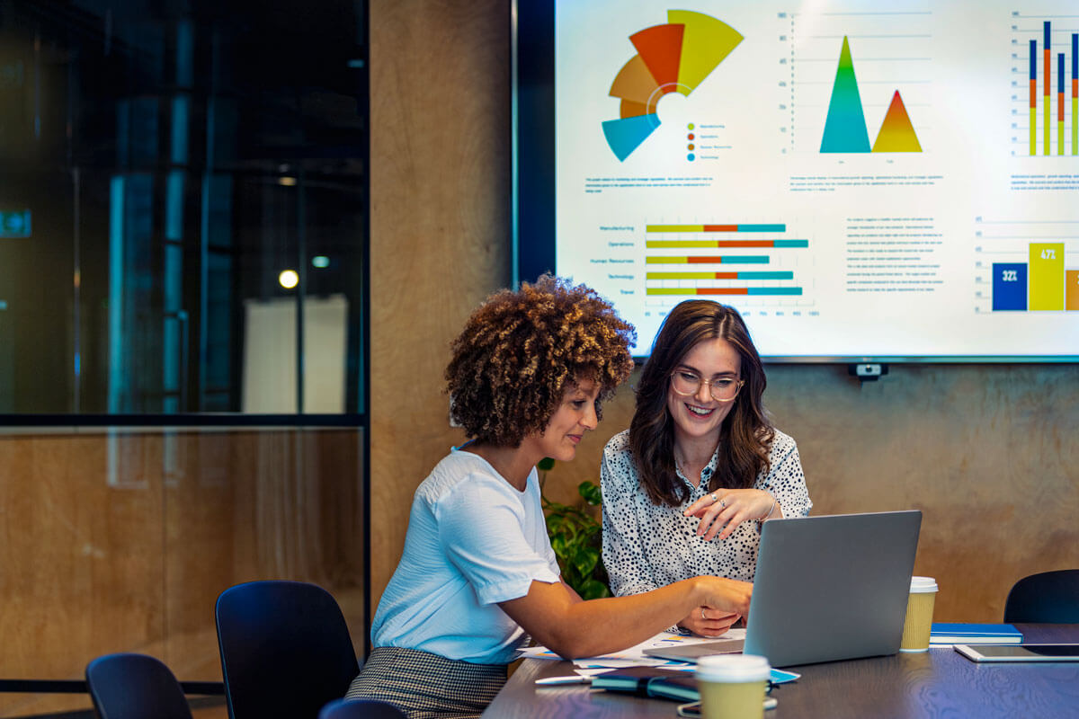 Two women looking at a laptop together.