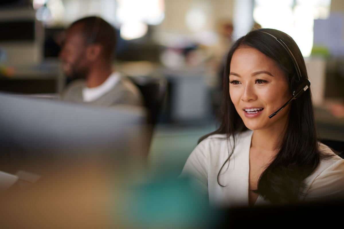 Woman wearing a phone headset and working on a computer.