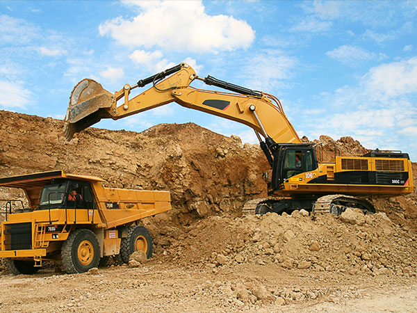 large excavator loading rock into a dump truck at a quarry