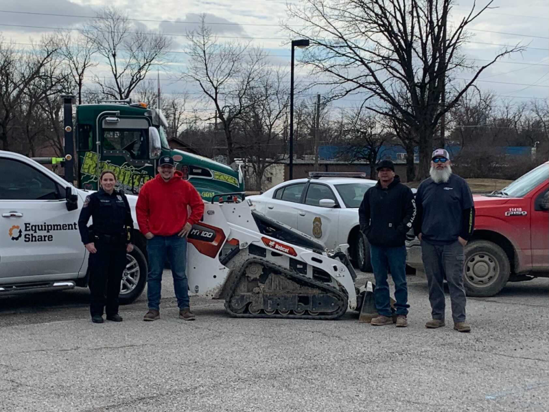 Four men posing with recovered bobcat dingo in parking lot