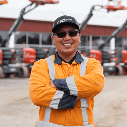 EquipmentShare employee wearing hi-vis gear with his arms crossed and smiling confidently.