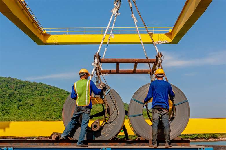 Two workers move spools of metal.