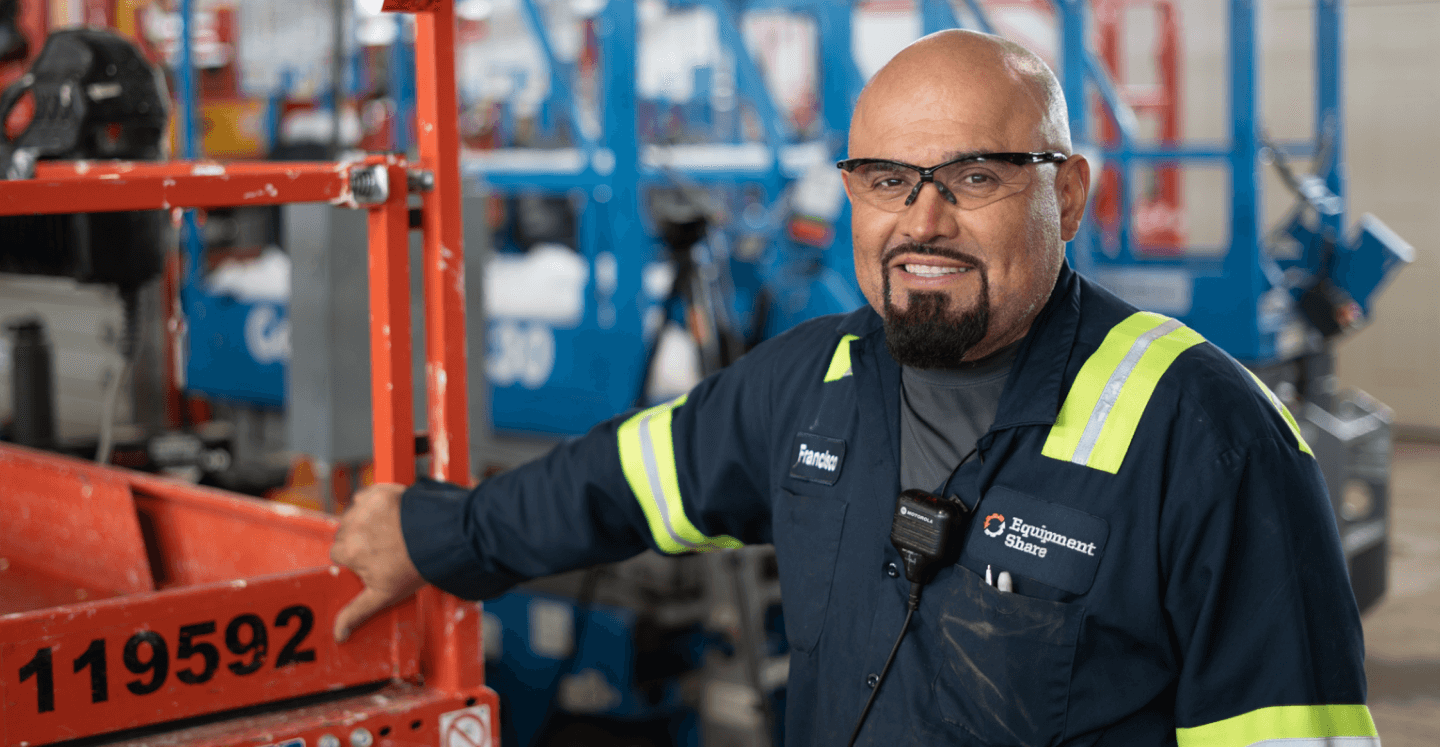 Man standing next to Equipment smiling.