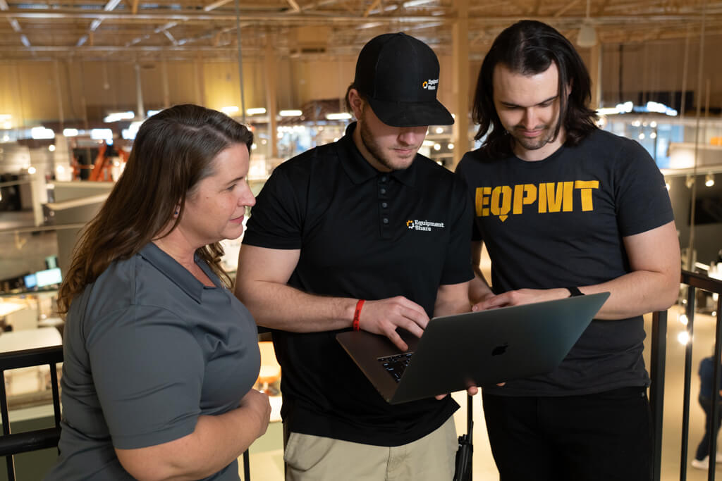a group of EquipmentShare employees inspecting something on a laptop