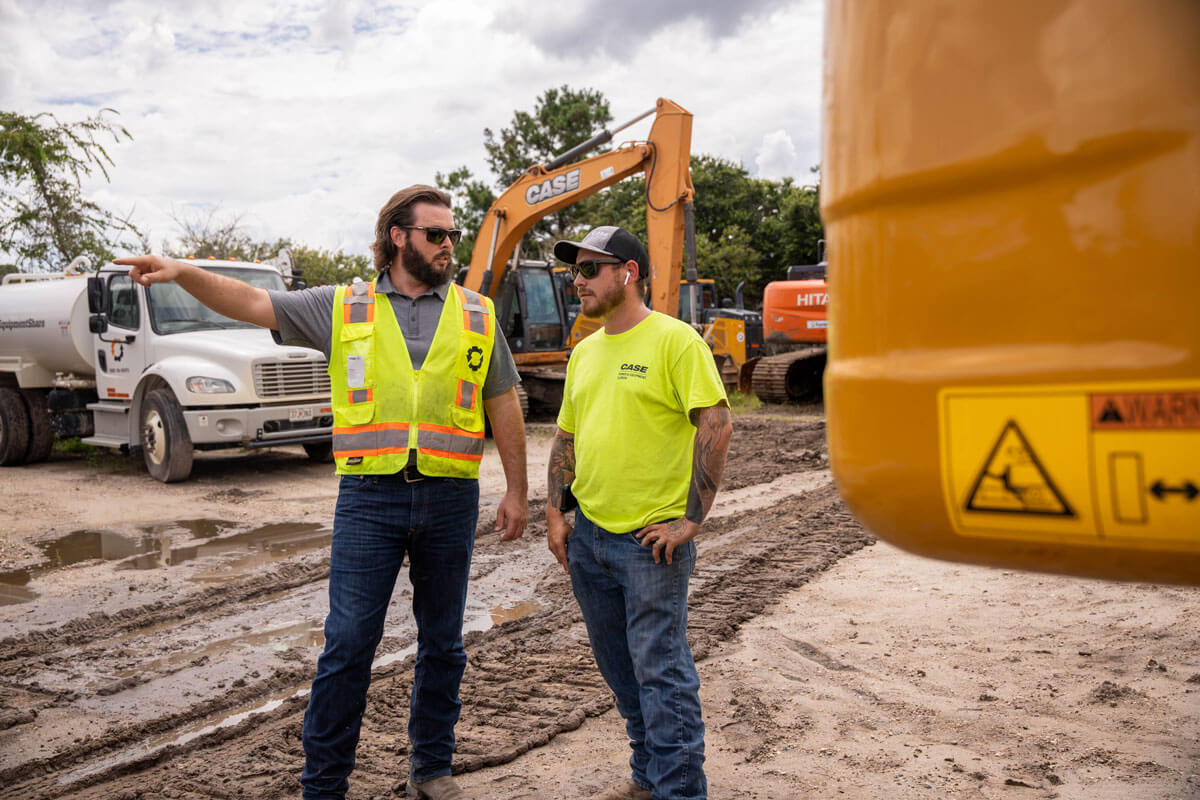 Two men in hi-vis talking on a jobsite.
