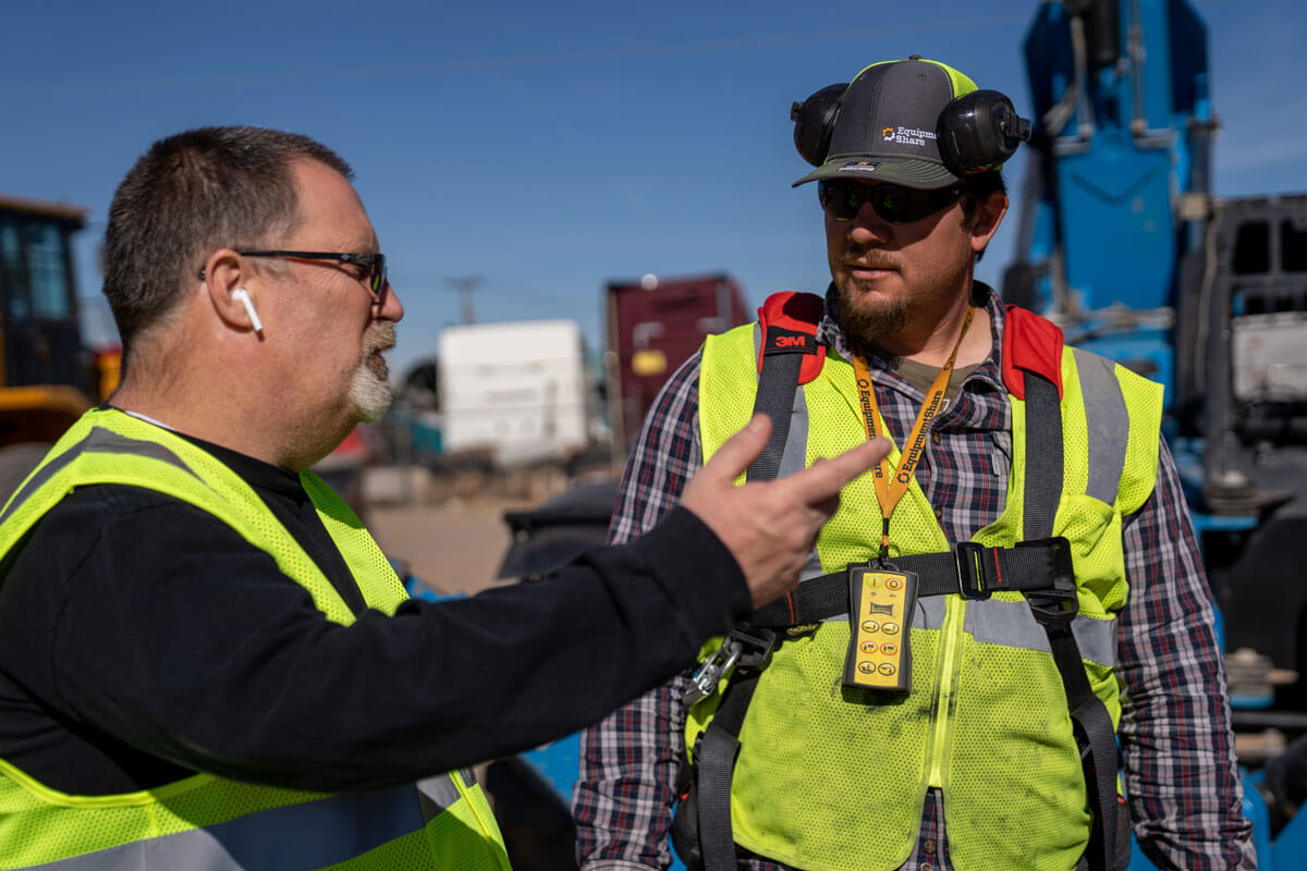 Two men wearing hi-vis clothes talking.