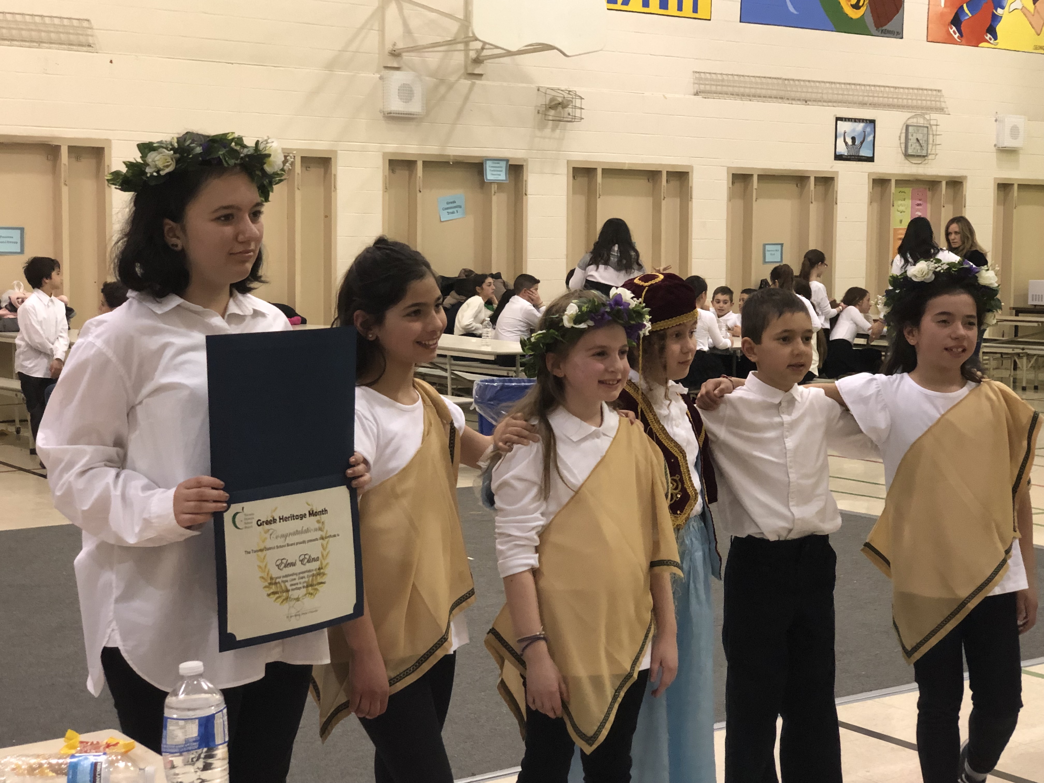Anna's daughter receiving an award for a Greek essay during Greek Heritage Month, 2019