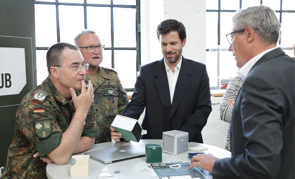 Four men standing around desk, debating