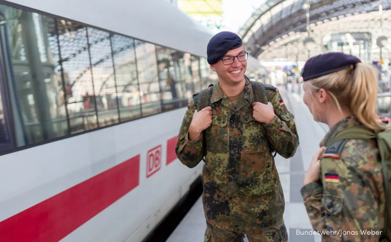 Man and woman in uniform standing before train
