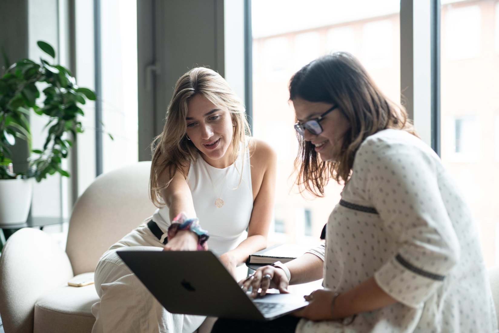 Two Woman sitting on chairs, watching a computer screen