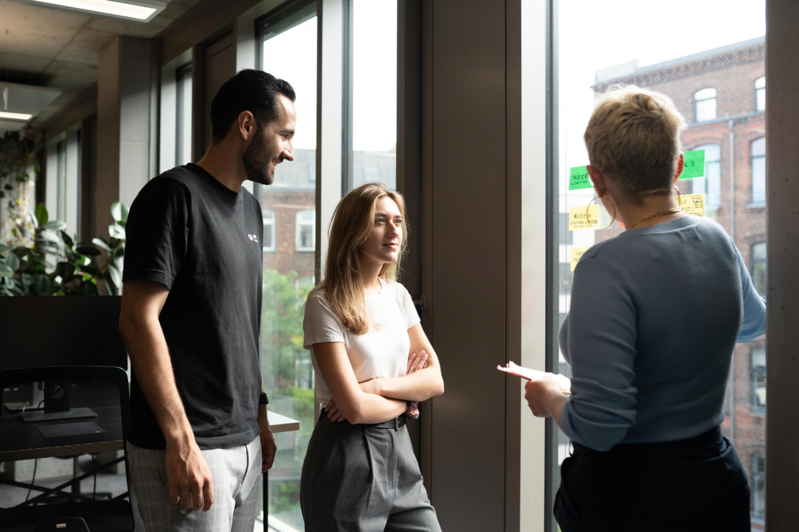 Man and two women having a conversation at a window with stickers on it