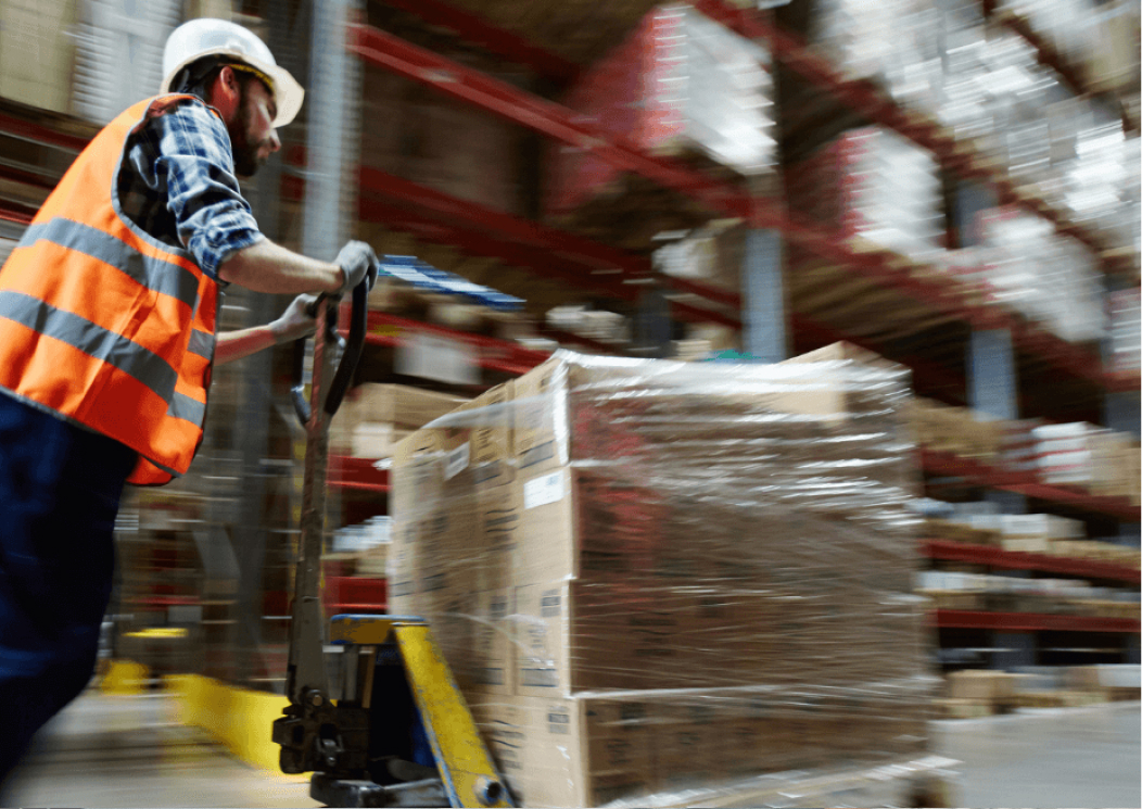 Man pushing down a cart in a warehouse.