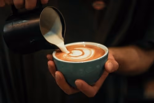 Person making latte art in blue cup