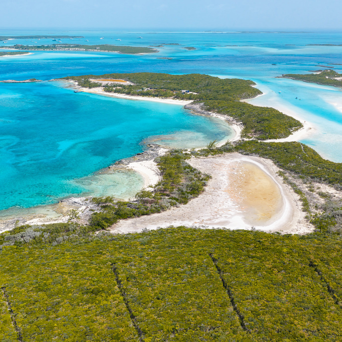 Aerial view of small tropical islands with lush green vegetation, white sandy beaches, and clear turquoise waters under a blue sky.
